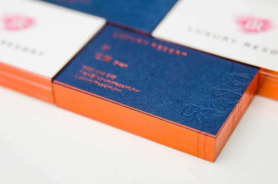 這張照片是一張深藍色有浮雕圖案的名片,名片周圍是橙色的邊框。