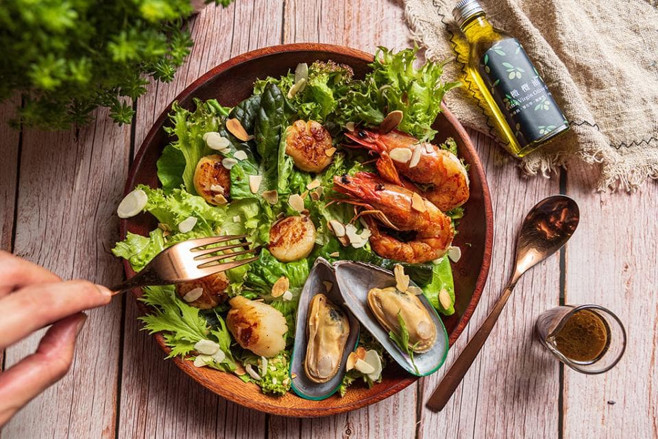 這張「沙拉」的照片是一個木碗裝的沙拉,裡面有生菜、蝦仁、幹貝和扇貝,還有一些堅果。