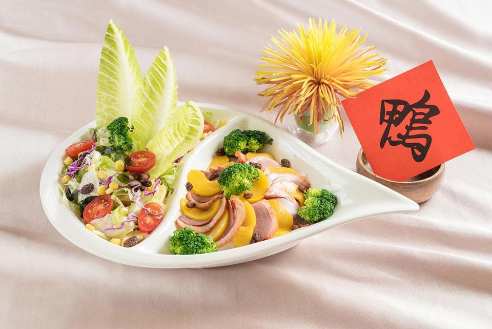 這張「菜餚」的照片是裝在一個白色盤子裡,左邊是生菜沙拉,右邊是黃色鴨肉。