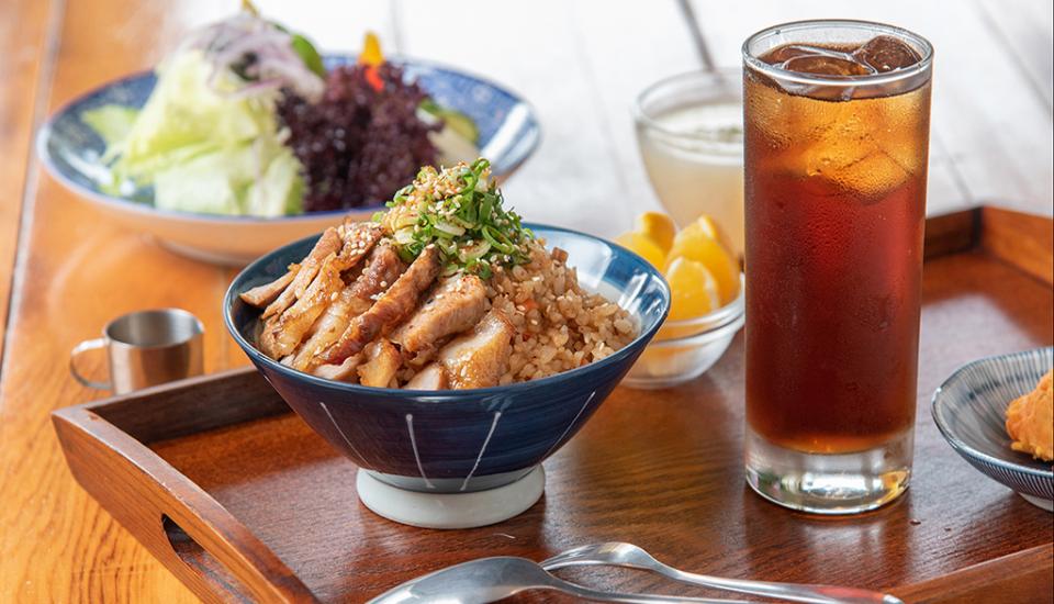 這張照片是一碗日式烤肉飯,配菜是清爽的沙拉和一杯冰涼的茶。