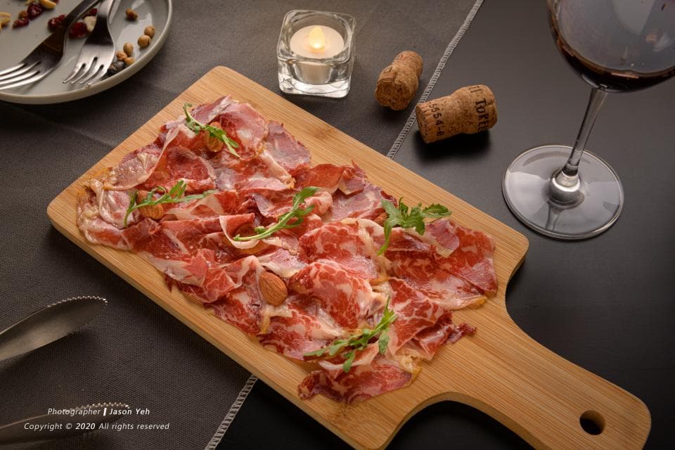 這張「木盤上擺著生火腿,搭配香草和堅果」的照片是。