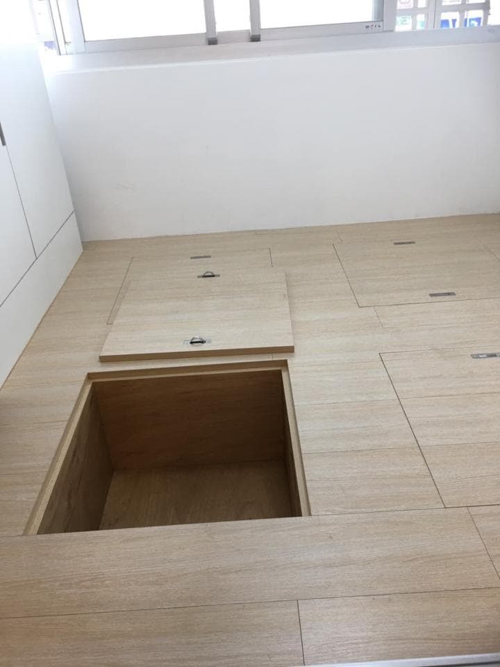 1) 照片顯示一個房間的木地板,地板上有三個木蓋,其中一個蓋子打開,露出一個方形的儲物空間