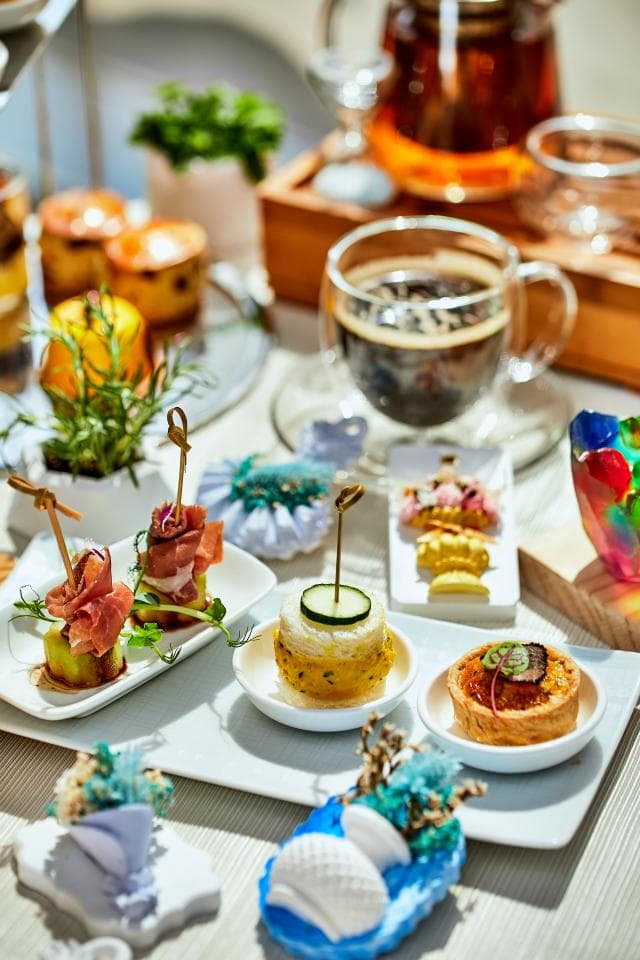 這張「下午茶」的照片是一張擺滿各種點心的餐桌,桌上擺著茶壺、茶杯、糕點、鹹點和水果,看起來非常豐盛美味。