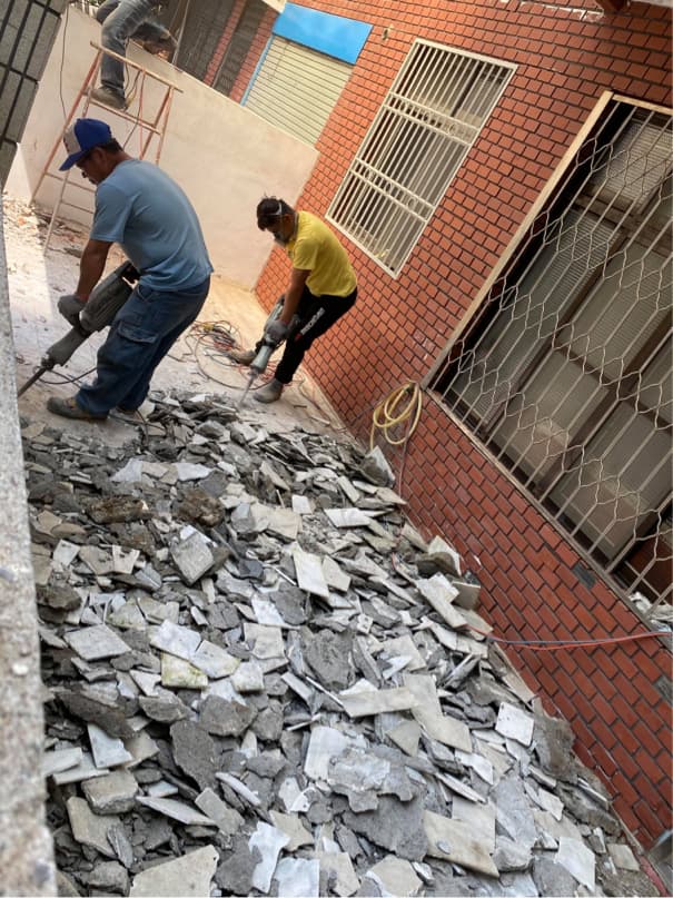 1) 照片顯示兩個工人正在拆除一棟建築物的石板瓦