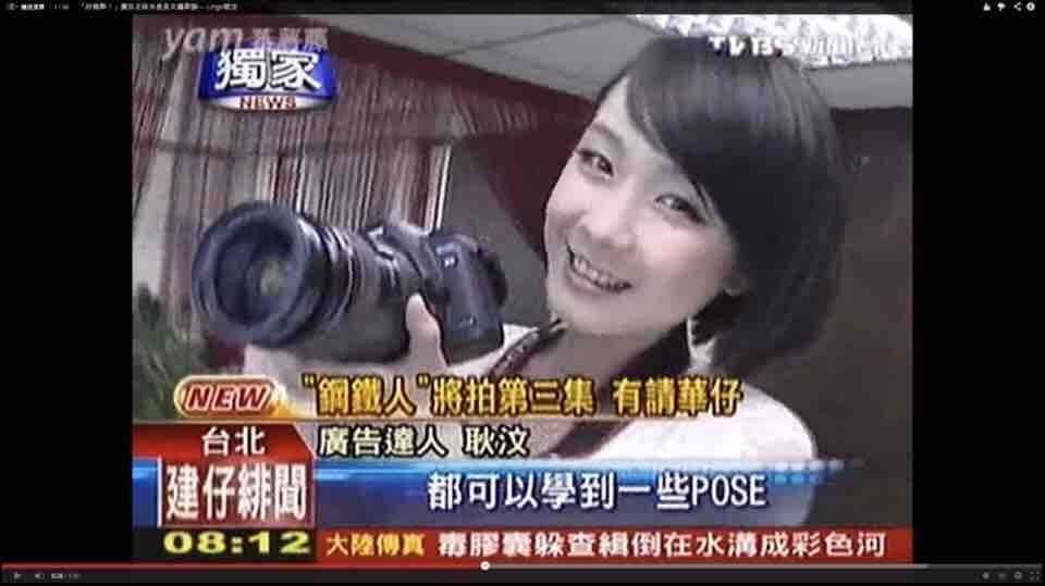 這張「一位年輕女性拿著攝影機,微笑著看鏡頭」的照片是。