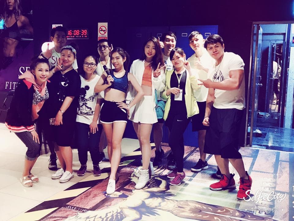 這張「一群朋友在健身房合照」的照片是,一群朋友在健身房裡,他們都穿著運動服裝,正在健身房裡合照。