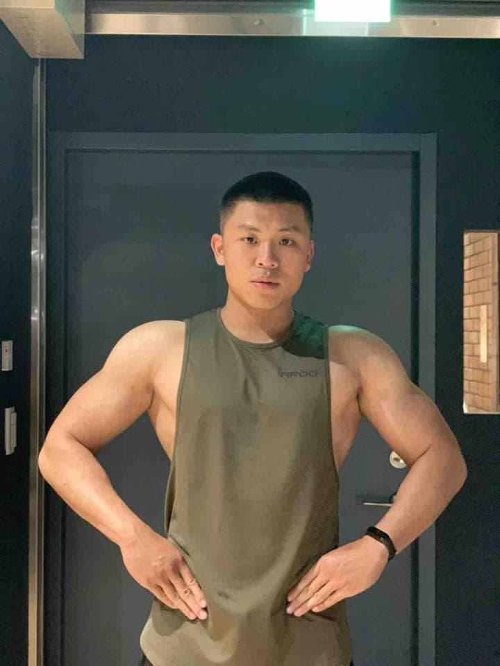 這張「一個穿著綠色背心,短髮,站在門前擺姿勢的年輕人」的照片是。