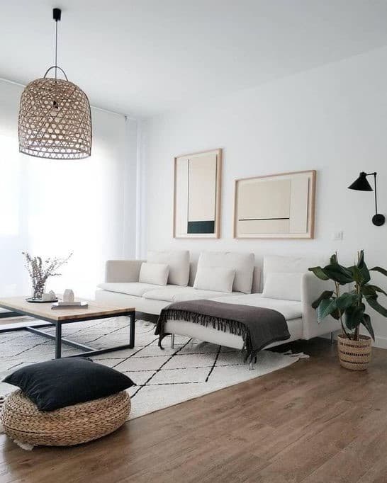 這張「客廳」的照片是一間現代風格的客廳,有一個白色的沙發,一個黑色的咖啡桌,一個編織的燈罩,兩幅抽象畫,一個編織的腳凳,和一盆綠色植物。