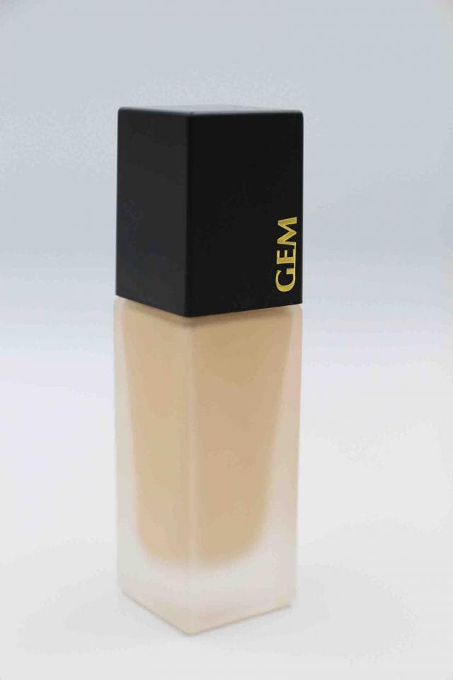 這張照片是一個化妝品瓶,瓶身是黑色,瓶蓋是金色,上面印著「GLAM」字樣。