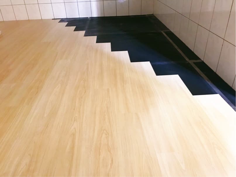 1) 照片顯示一個木地板,地板上有黑色防水材料