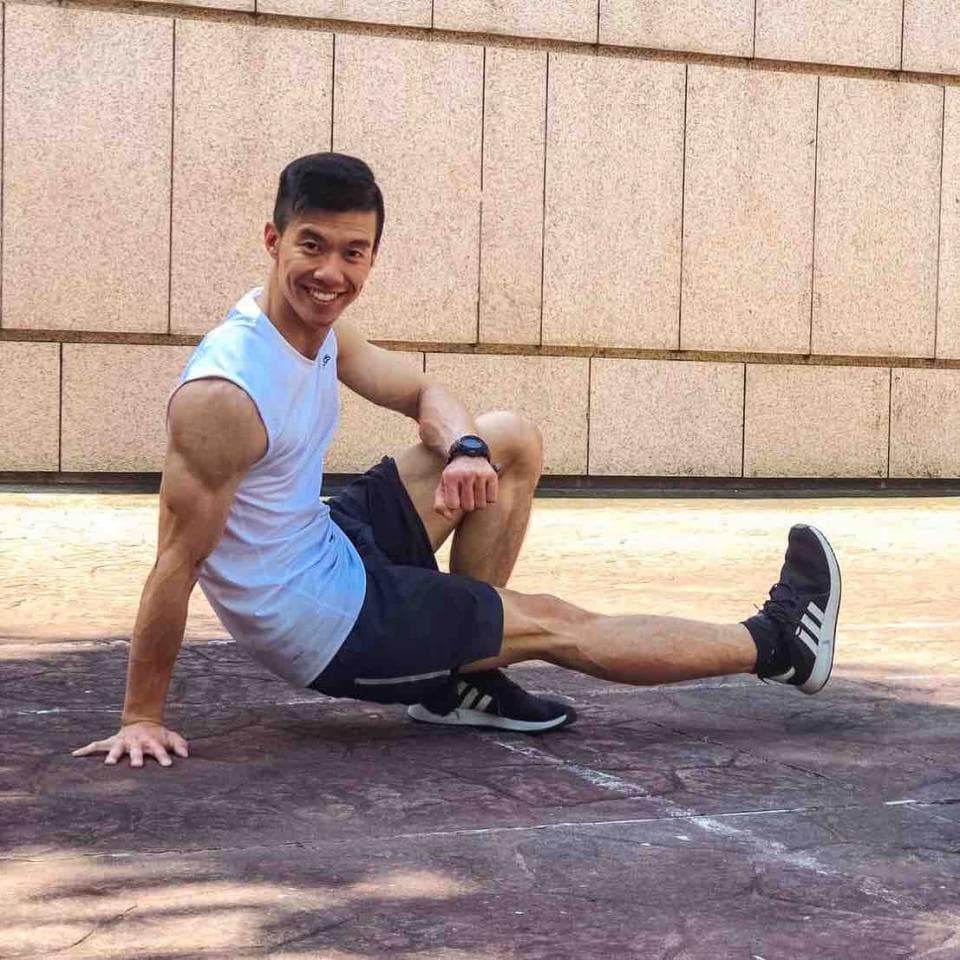 這張「一個男人正在做運動」的照片是,他穿著白色背心和黑色短褲,正在做一個伸展動作。他看起來很健康和充滿活力。