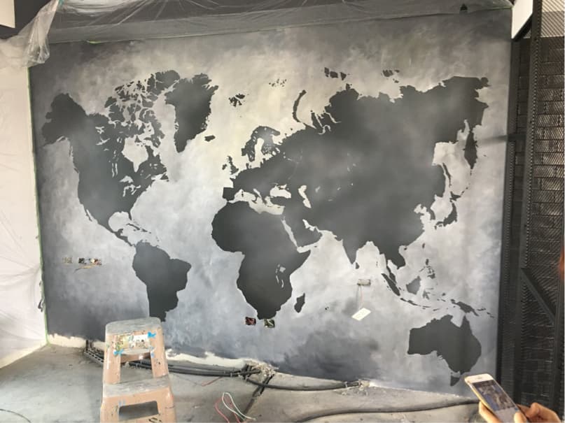 這張「世界地圖」的照片是一幅牆上的世界地圖壁畫,用黑色塗料繪製在灰白色牆上。
