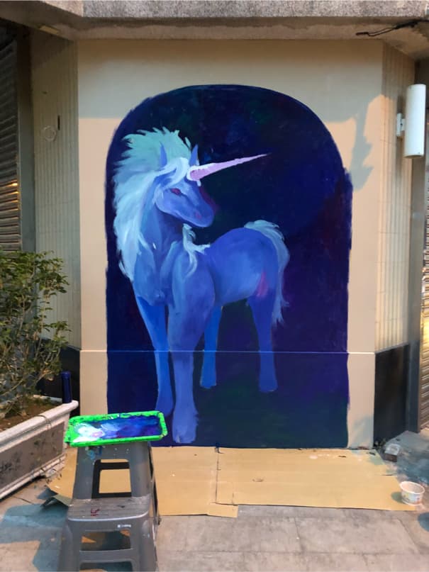 這張「牆上繪畫」的照片是一隻藍色的獨角獸,它正在一堵牆上被畫出來。牆壁是藍色的,獨角獸是白色的。它看起來很漂亮。