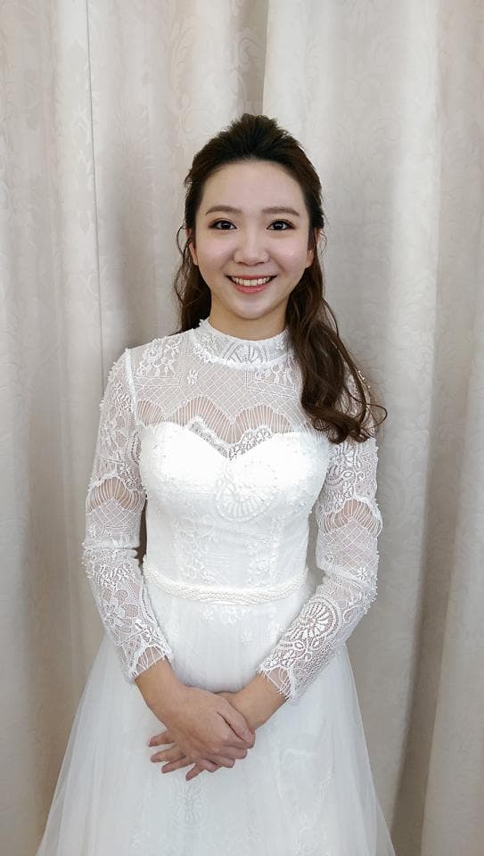 這張照片是一位穿著白色蕾絲婚紗的女性,她面帶笑容,看起來非常開心。