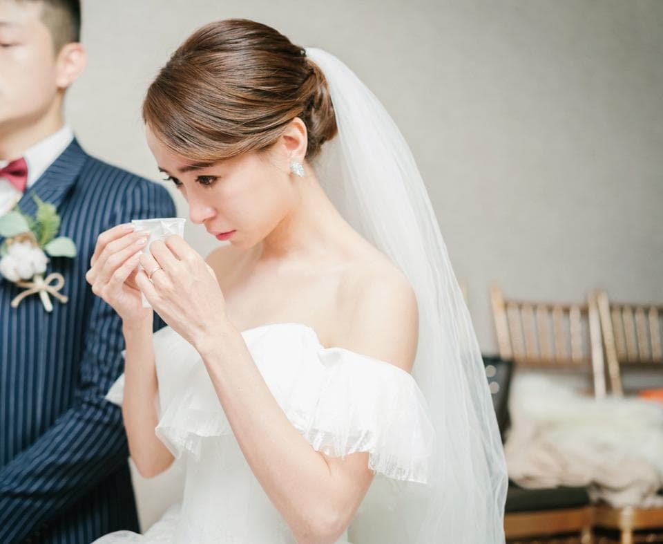 這張照片是一個新娘穿著婚紗,她用手帕拭去眼淚。