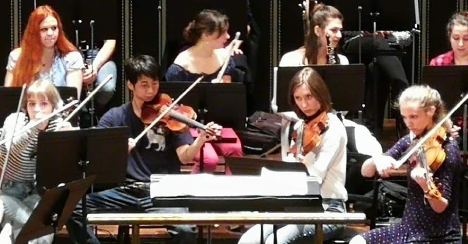 1) 照片中,七位年輕人正在演奏樂器,背景是音樂廳的舞台