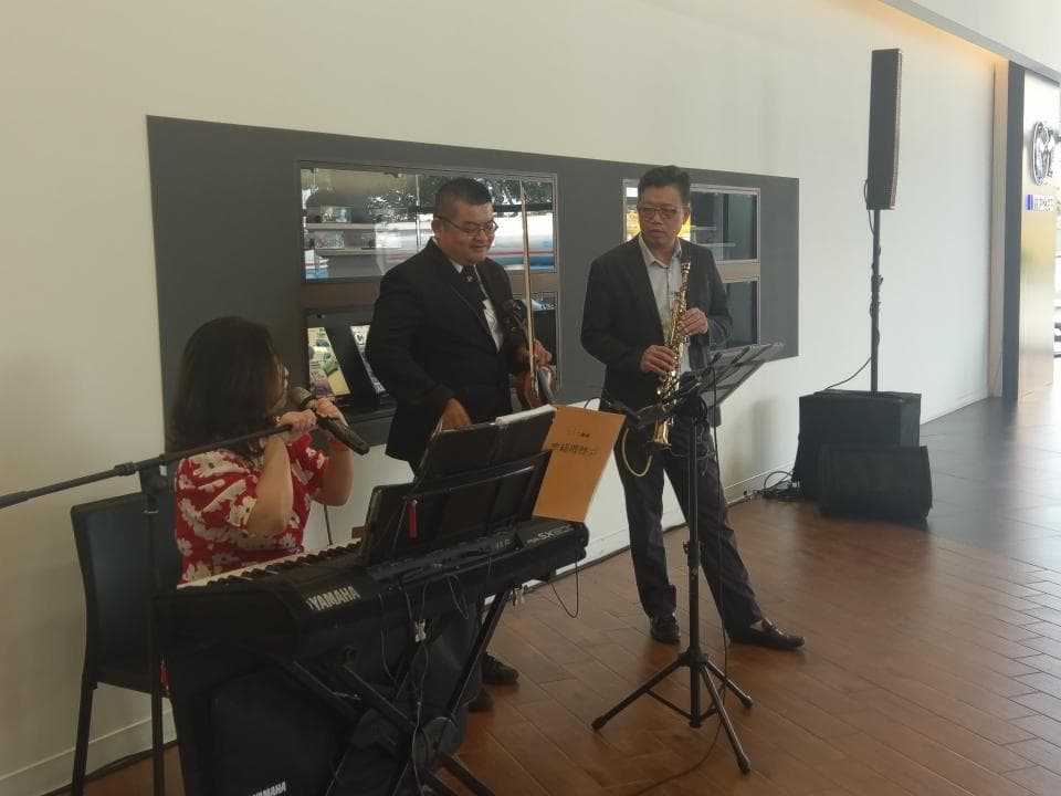 這張「音樂演奏」的照片是一場小型音樂表演,有三位音樂家在演奏:一位女歌手,一位小提琴手和一位薩克斯風手。