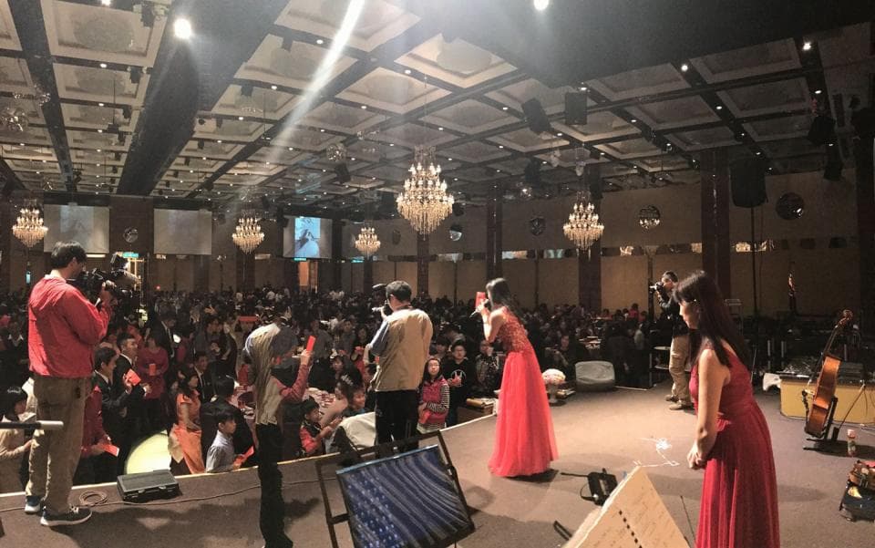 這張照片是婚禮現場,兩位新娘正在台上表演唱歌。