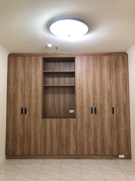 這張照片是一間房間裡的木製衣櫃,中間有一個開放式層架,可以放一些擺飾品或書籍。