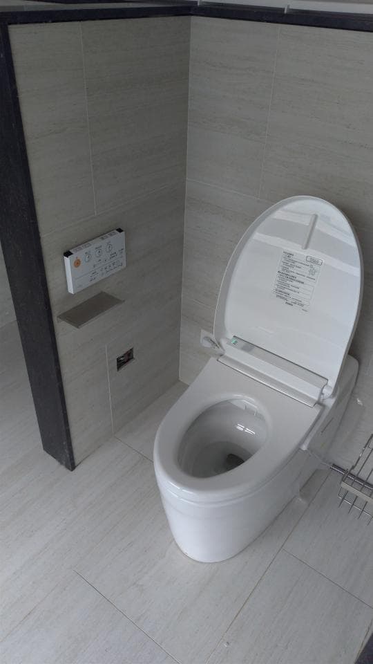 1) 照片中展示了一个白色的智能马桶,它位于一个带有浅色瓷砖的浴室里