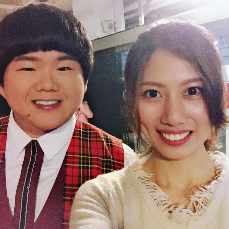 這張照片是兩位朋友的合照,其中一位穿著紅黑格紋的西裝外套,另一位穿著白色毛衣,兩個人都面帶笑容,看起來很開心。