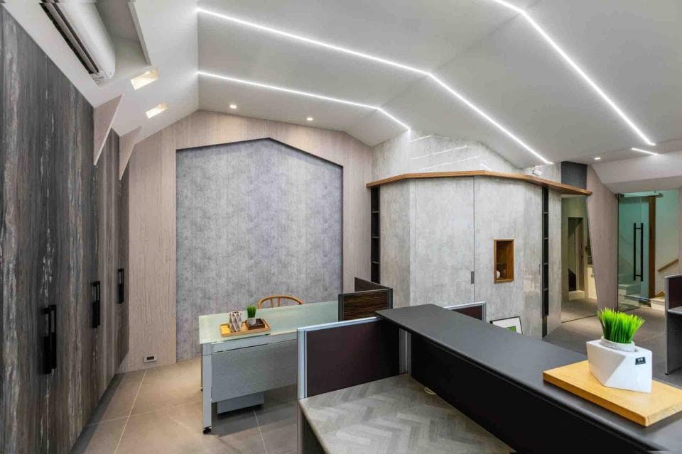 這張辦公室的照片是一個現代化的辦公空間,設計簡潔,以灰白色調為主,並有木質元素點綴,整體看起來非常明亮舒適。