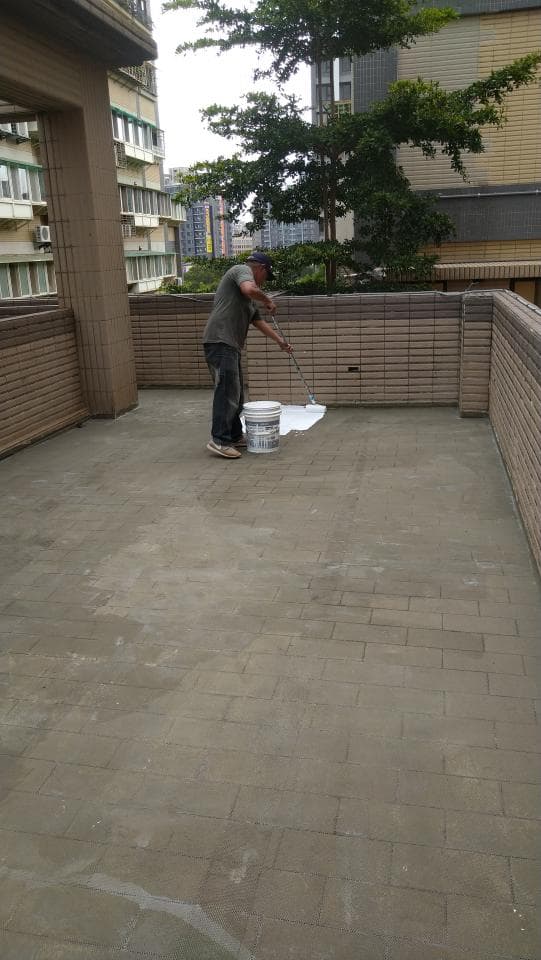 這張照片是一名男子正在陽台刷水泥。