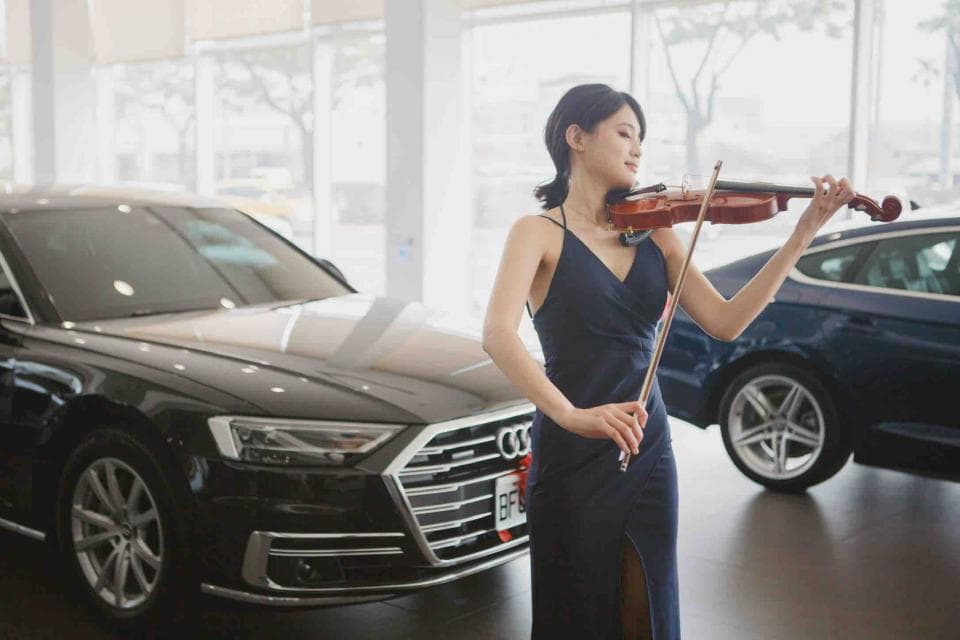 這張照片是一個穿著黑色禮服的女子,她正在演奏小提琴。