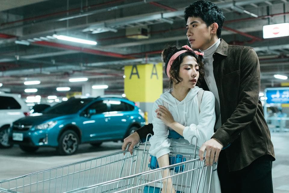 這張「停車場」的照片是一對男女在推購物車,他們身後停著一輛藍色的汽車。