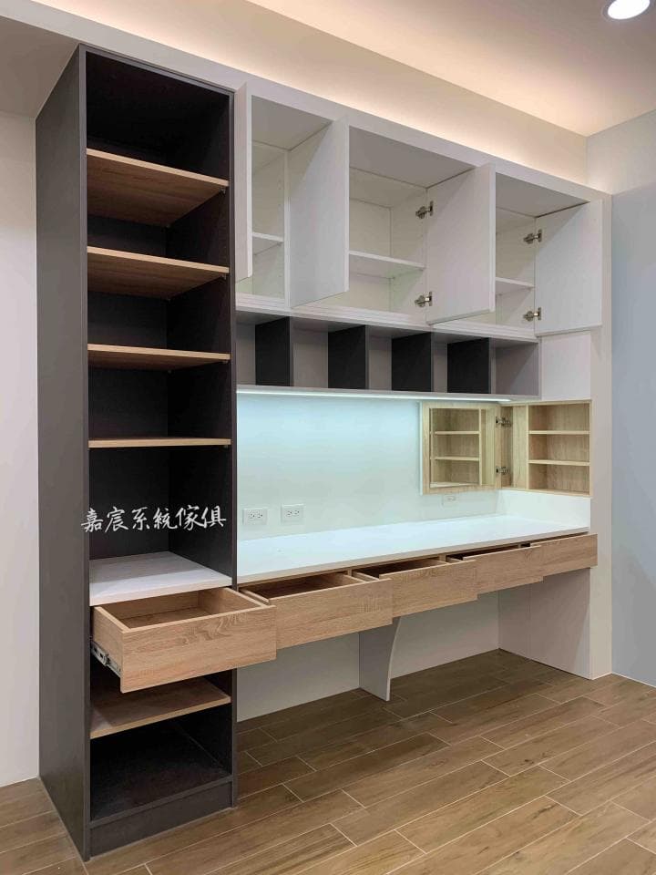 這張照片是展示一個現代化的書桌,它結合了書架、抽屜和櫃子,方便使用者整理和儲物。書桌的設計簡潔美觀,適合現代家居風格。