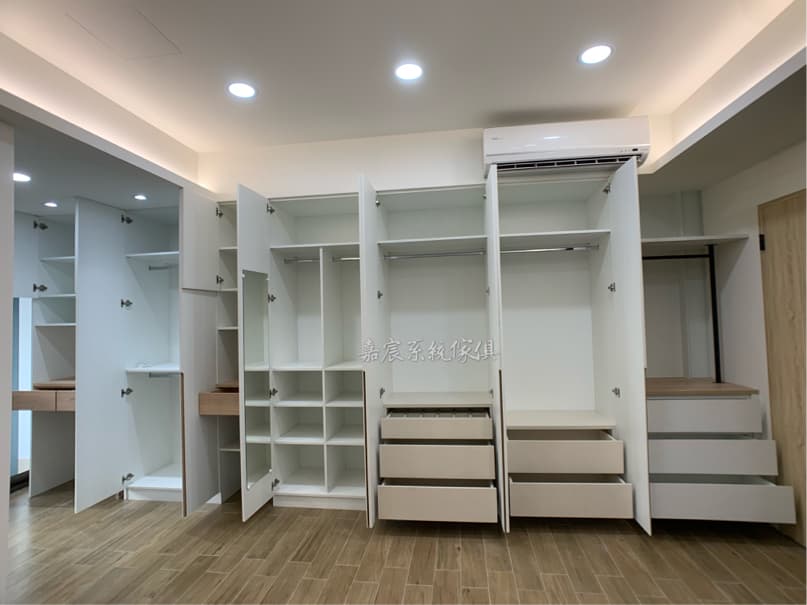 這張照片是一個現代化的衣帽間,最大的特色是採用了大量的白色櫃體,搭配木紋色的抽屜,整體看起來簡潔大方,而且非常實用。