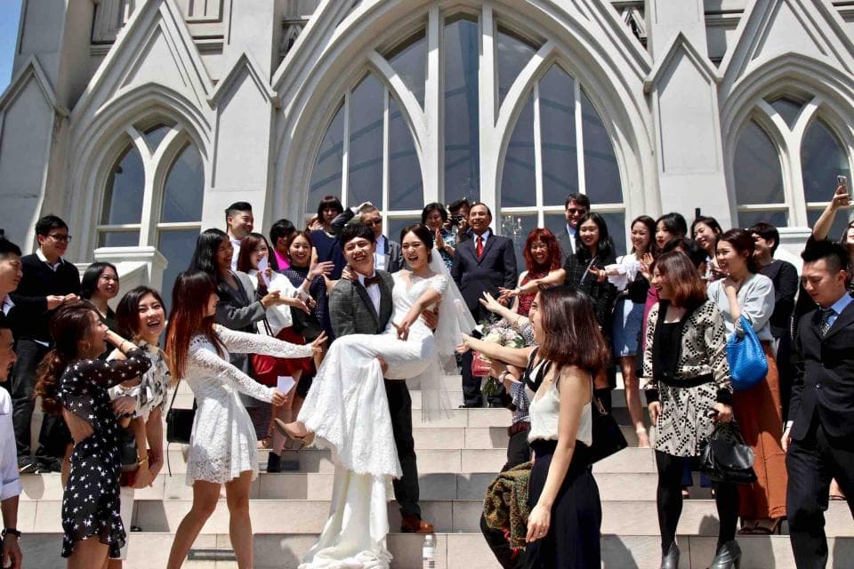 這張照片是一對新人在教堂門外舉行婚禮,新郎將新娘抱起,並親吻她。