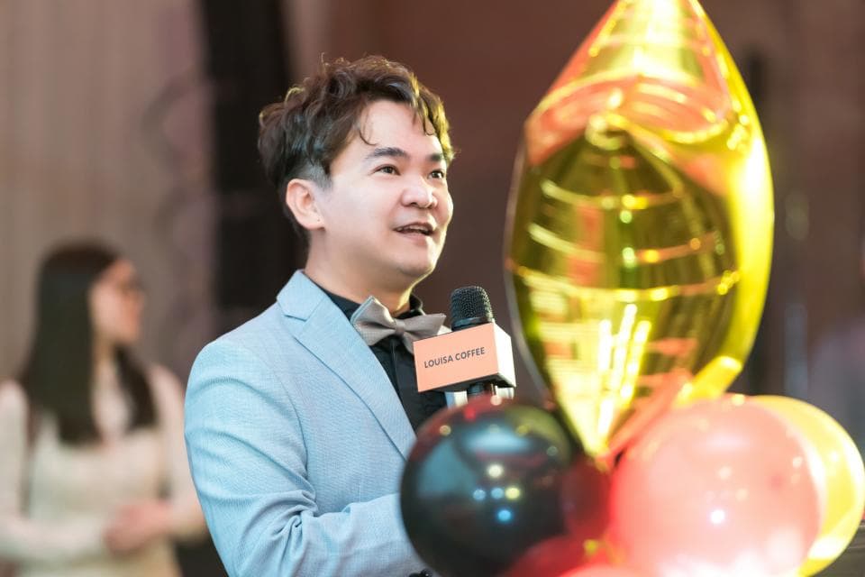 這張「男人在金色氣球背景下演講」的照片是,男人穿著灰色西裝,戴著領帶,拿著麥克風,正在演講。他後面是一些氣球,其中一顆是金色的,顯得很醒目。