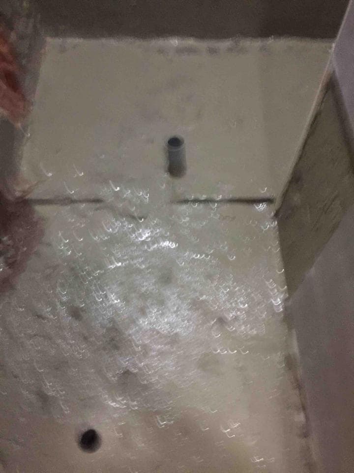 1) 照片顯示一個白色的浴室,地上有水,牆壁上有灰泥