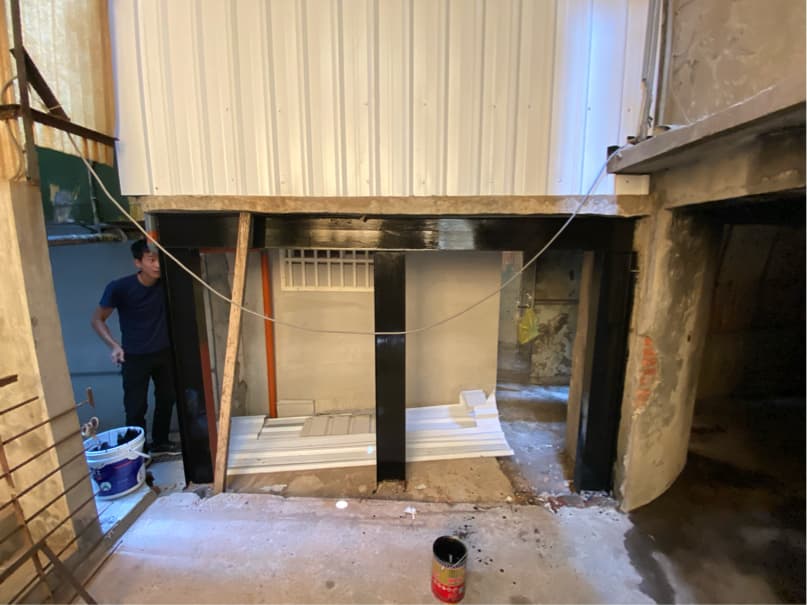 1) 照片顯示一間正在施工的建築物,牆壁上有黑色樑柱