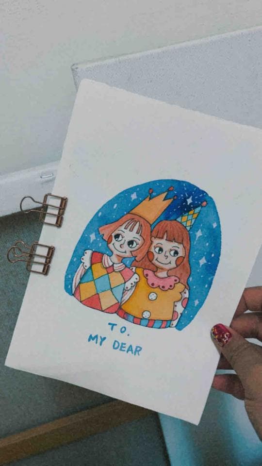 這張照片是一張手繪的卡片,卡片上畫著兩個穿著可愛服裝的女孩,女孩們親密地靠在一起,背景是藍色的星空。最重要的是卡片下方寫著 "TO. MY DEAR",這顯示這是一張充滿愛意和溫馨的卡片。