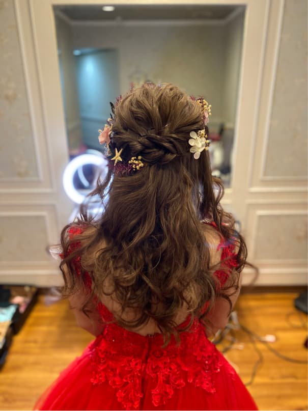 這張照片是一個女孩穿著紅色蕾絲禮服,頭上戴著花朵髮飾,看起來很漂亮。