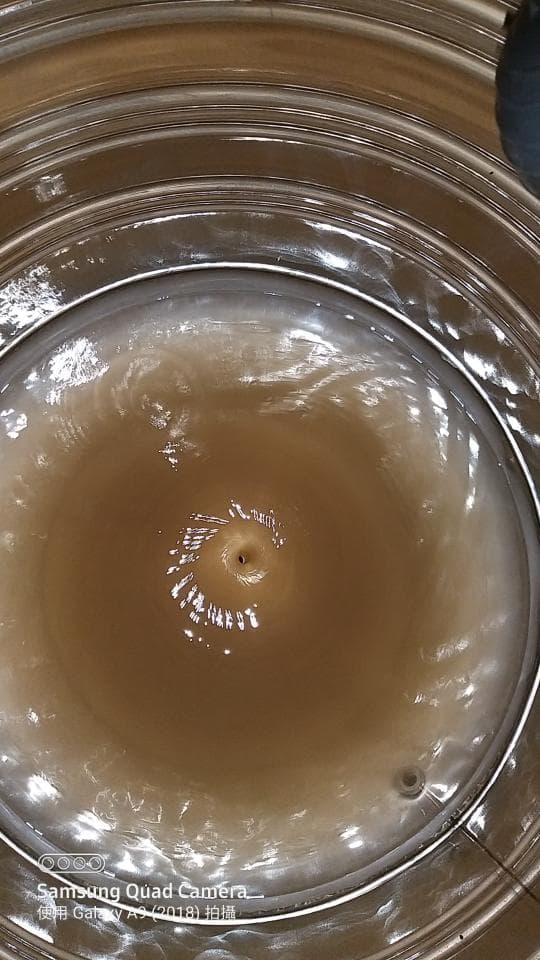 1) 照片顯示一個圓形容器,裡面裝滿水,水正從中央的小孔中流出,形成一個漩渦