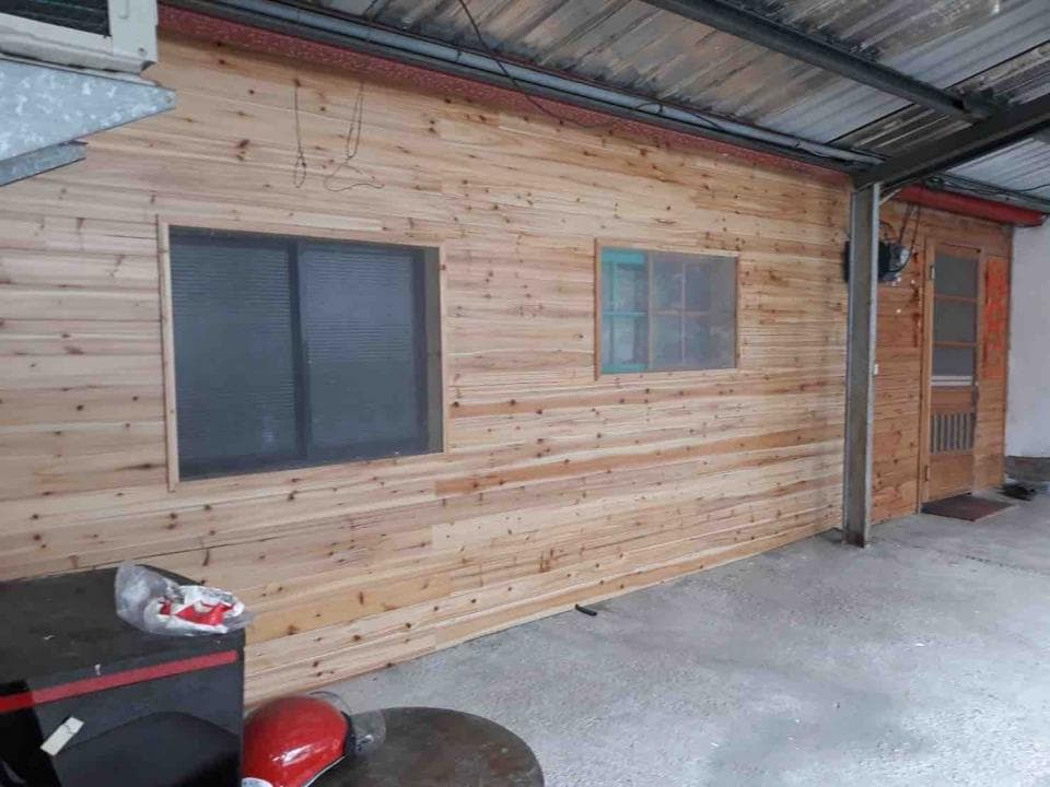 1) 照片顯示一棟木板外牆的房子,外牆上有兩個窗戶和一扇門