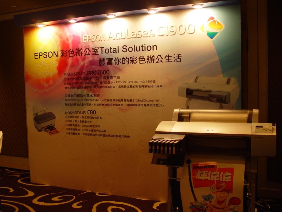1) 照片顯示一台愛普生印表機,有墨盒,旁邊還有廣告文宣