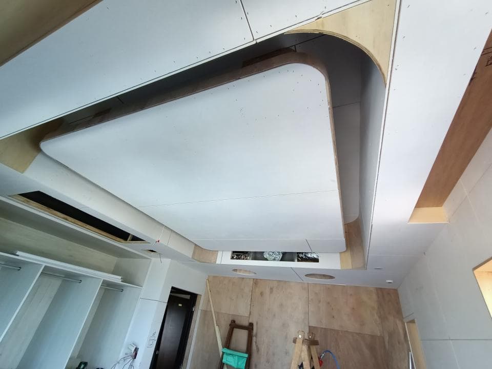 這張照片是一間房子正在裝修的房間,照片中最重要的是天花板,天花板上的造型設計非常特別,使用了多層板材,做出一個凹陷的造型,看起來非常現代感。