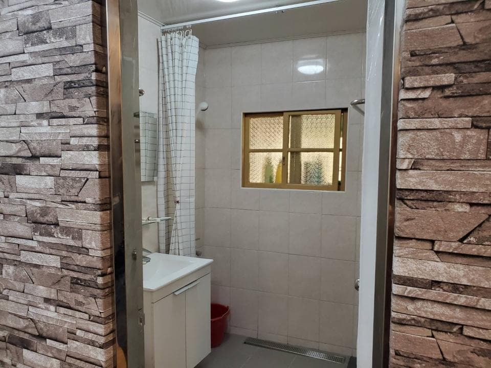 1) 照片顯示一間浴室,浴室的牆壁是白色磁磚,浴室配有淋浴間和一個洗手台