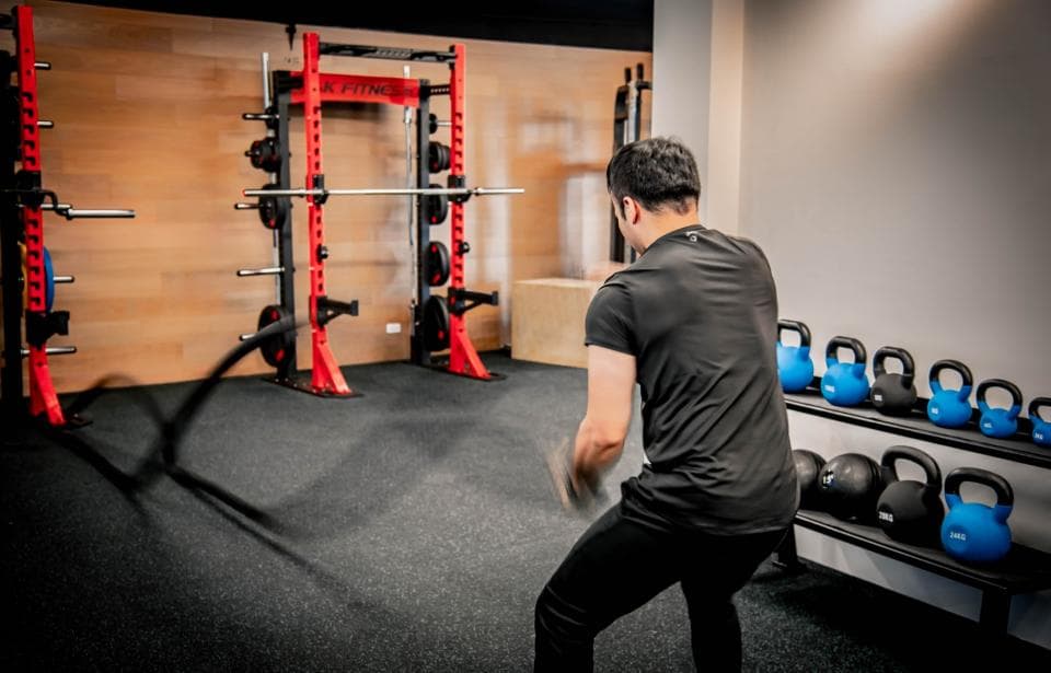 這張照片是一名男子在健身房裡使用健身繩進行訓練。