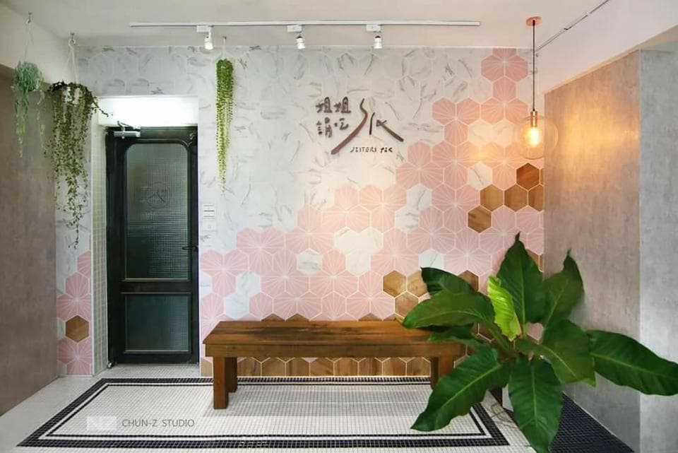 這張「室內設計」的照片是一間餐廳的入口,牆上裝飾著粉色和木色的六角形磁磚,並搭配綠色植物和一盞吊燈,營造出舒適又時尚的氛圍。