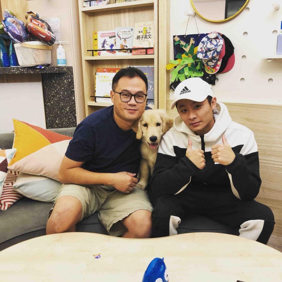 這張照片是一個家庭聚會,一個男人,一個男孩,和一隻金毛獵犬。他們都很開心,狗狗在男人和男孩的腿上。