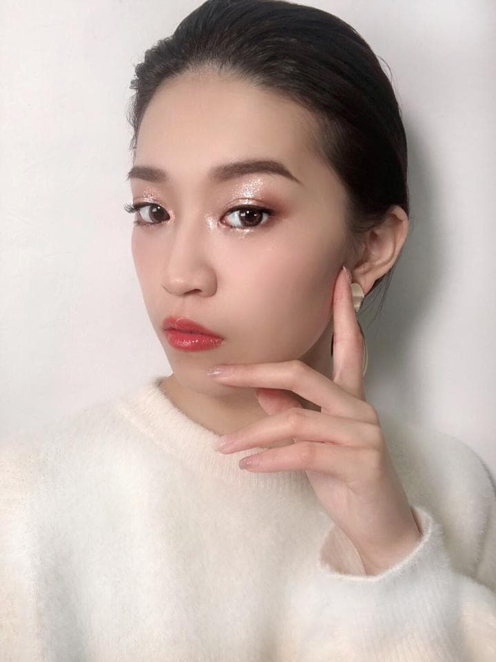 這張「年輕女性肖像」的照片是,她留著黑色短髮,穿著白色毛衣,手放在下巴,看起來很漂亮。她化著精緻的妝容,眼神迷人。