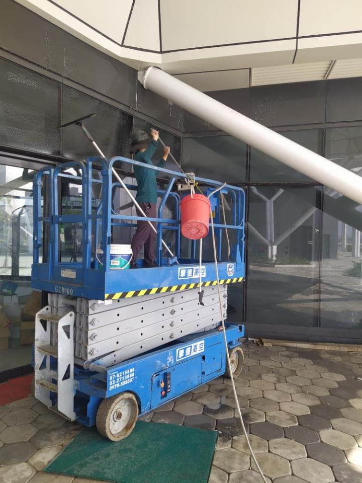 1) 照片顯示一名工人站在升降機上,使用刷子清潔玻璃窗