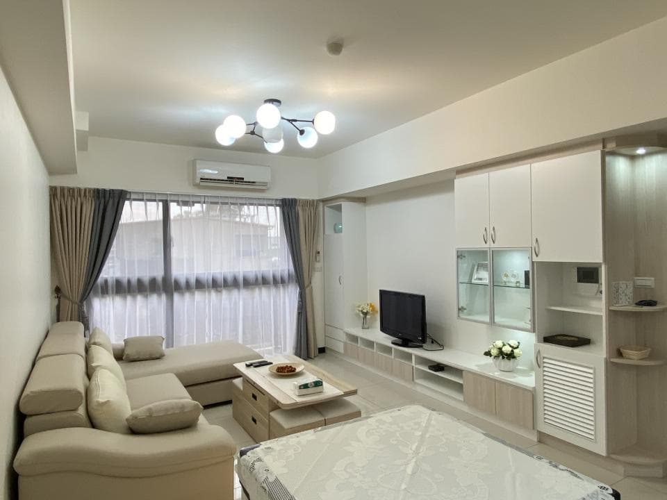 1) 照片顯示一個現代化的客廳,有一個白色的沙發,一張咖啡桌,以及一個大型的白色電視櫃