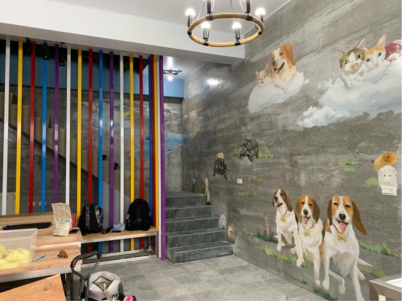 這張「寵物美容院」的照片是一間充滿童趣的店面,牆壁上畫滿了可愛的動物,地板上鋪著淺灰色的磁磚,看起來很乾淨整潔。