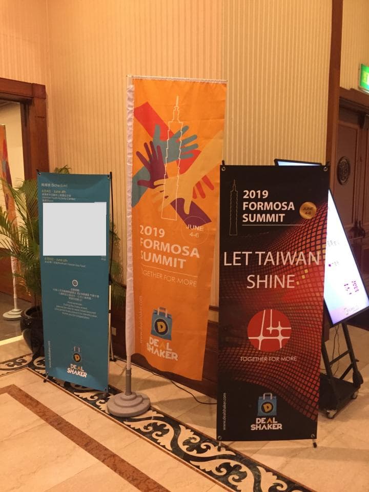 這張「2019 Formosa Summit」的照片是在一個會議室裡,裡面有三個展板,其中一個展板上面寫著「Let Taiwan Shine」。